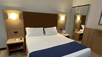 Ein Hotelzimmer mit einem großen Bett, Nachttischen, einem Spiegel und Holzboden.