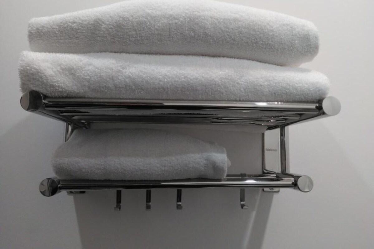 A stack of white towels on a chrome towel rack.