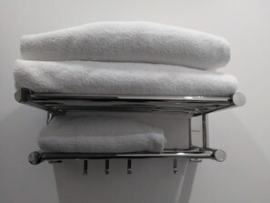 A stack of white towels on a chrome towel rack.