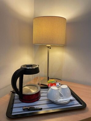 A table with a kettle, cups, and a tray, a lamp, and a wall-mounted lamp. - Residenza Cola di Rienzo - Suite In Rome (Rome)