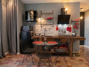 A compact kitchen with a dining area, featuring a sink, stove, and a small refrigerator. - Volta 45: An Elegant Loft in the Heart of Testaccio (Roma)