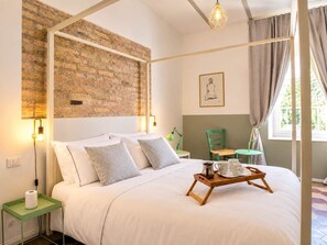 Un lit à baldaquin avec un mur en briques en arrière-plan, une table de chevet avec une lampe et une fenêtre avec des rideaux.