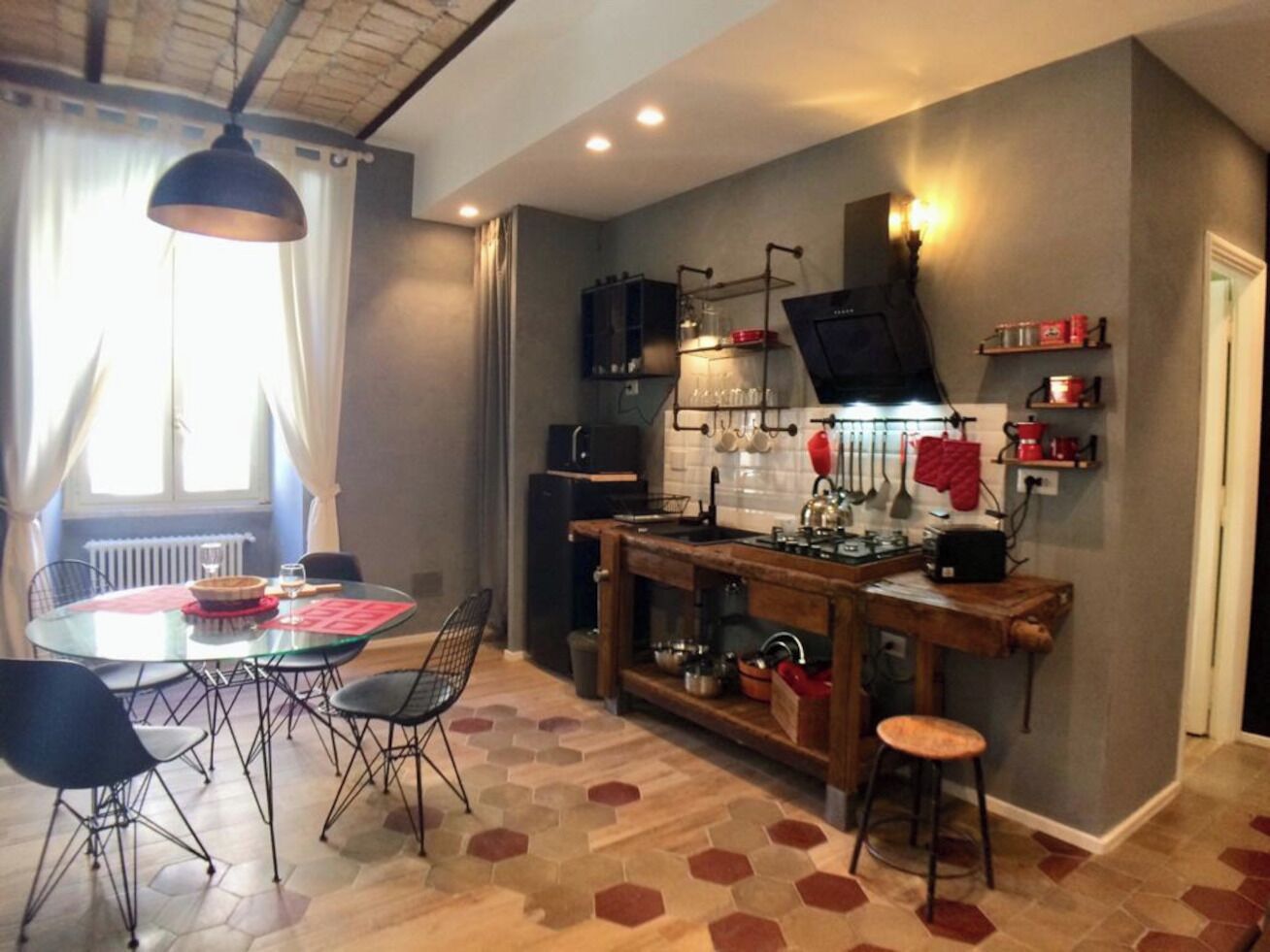 Een kleine keuken met een ronde eettafel, stoelen, een houten bar en een ingebouwde oven.