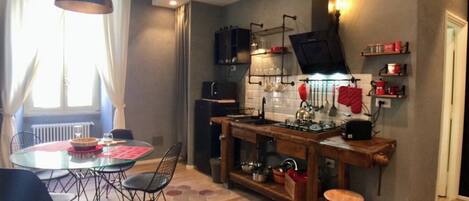 Una cocina compacta con una mesa redonda de comedor, sillas, una barra de bar de madera y un horno empotrado.