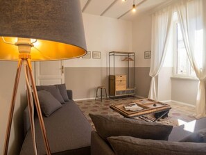 Un salon avec un canapé, une table basse, une lampe et une fenêtre avec des rideaux.