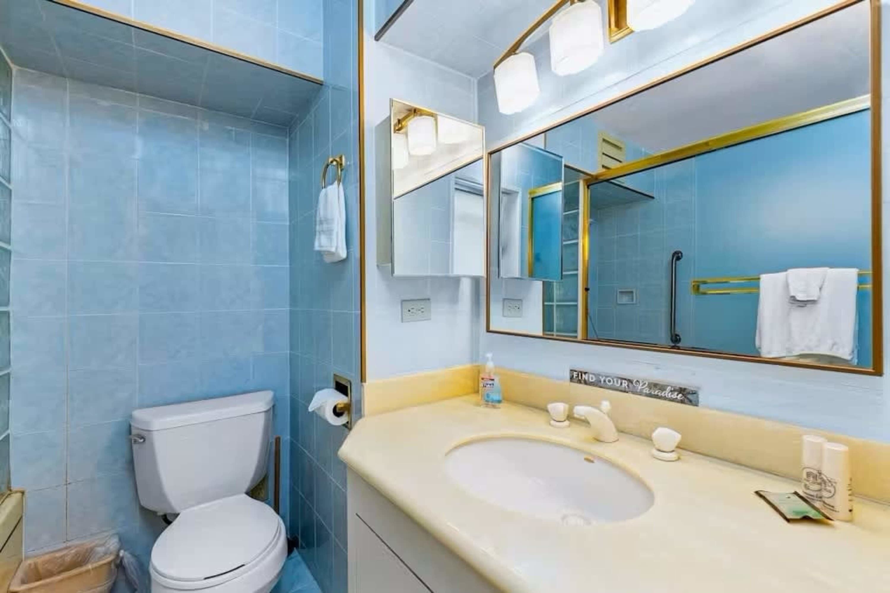 A bathroom with a toilet, sink, and mirror.