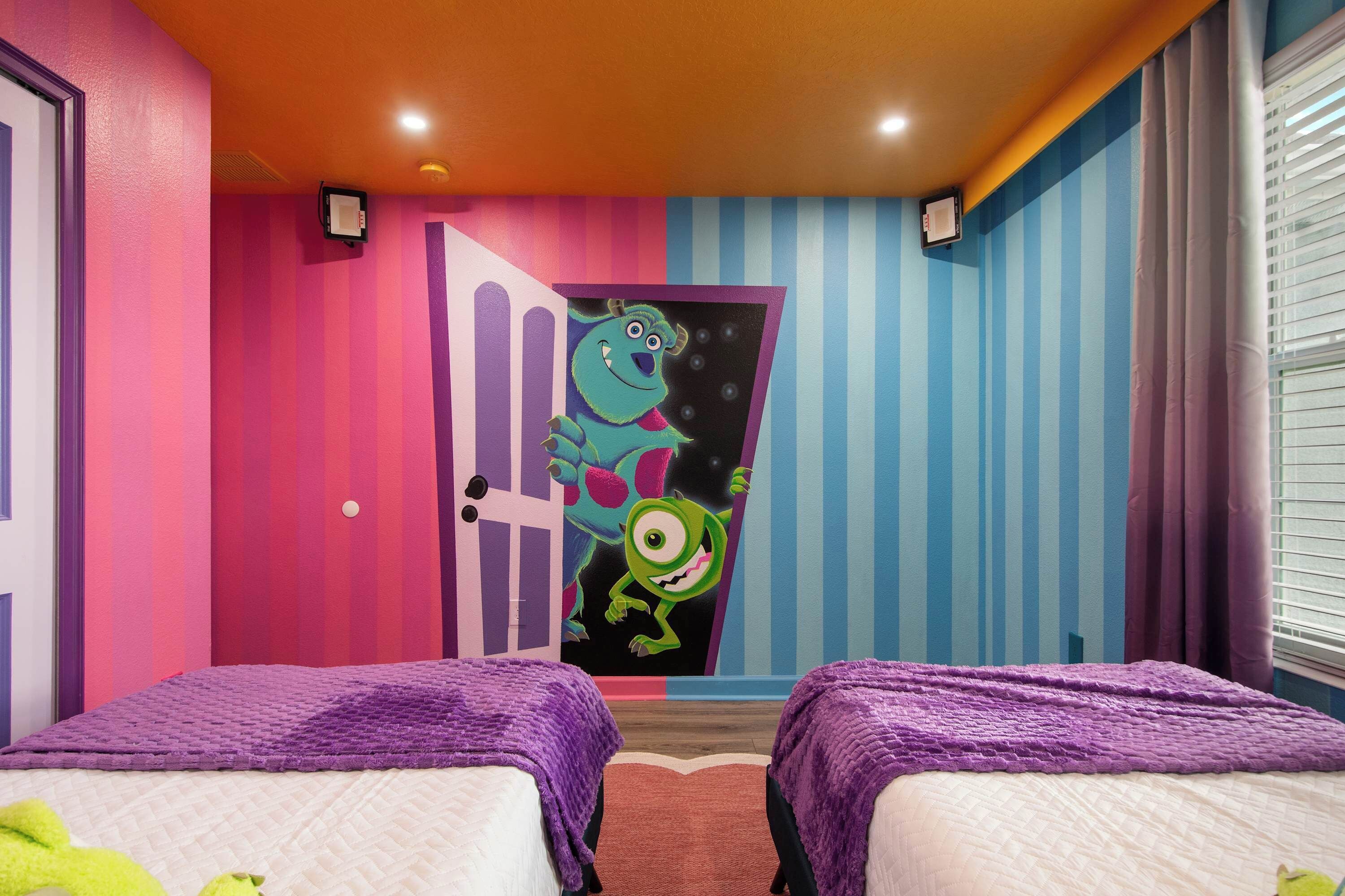 A room with two beds, a colorful door, and a window with blinds.