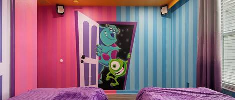 A room with two beds, a colorful door, and a window with blinds.