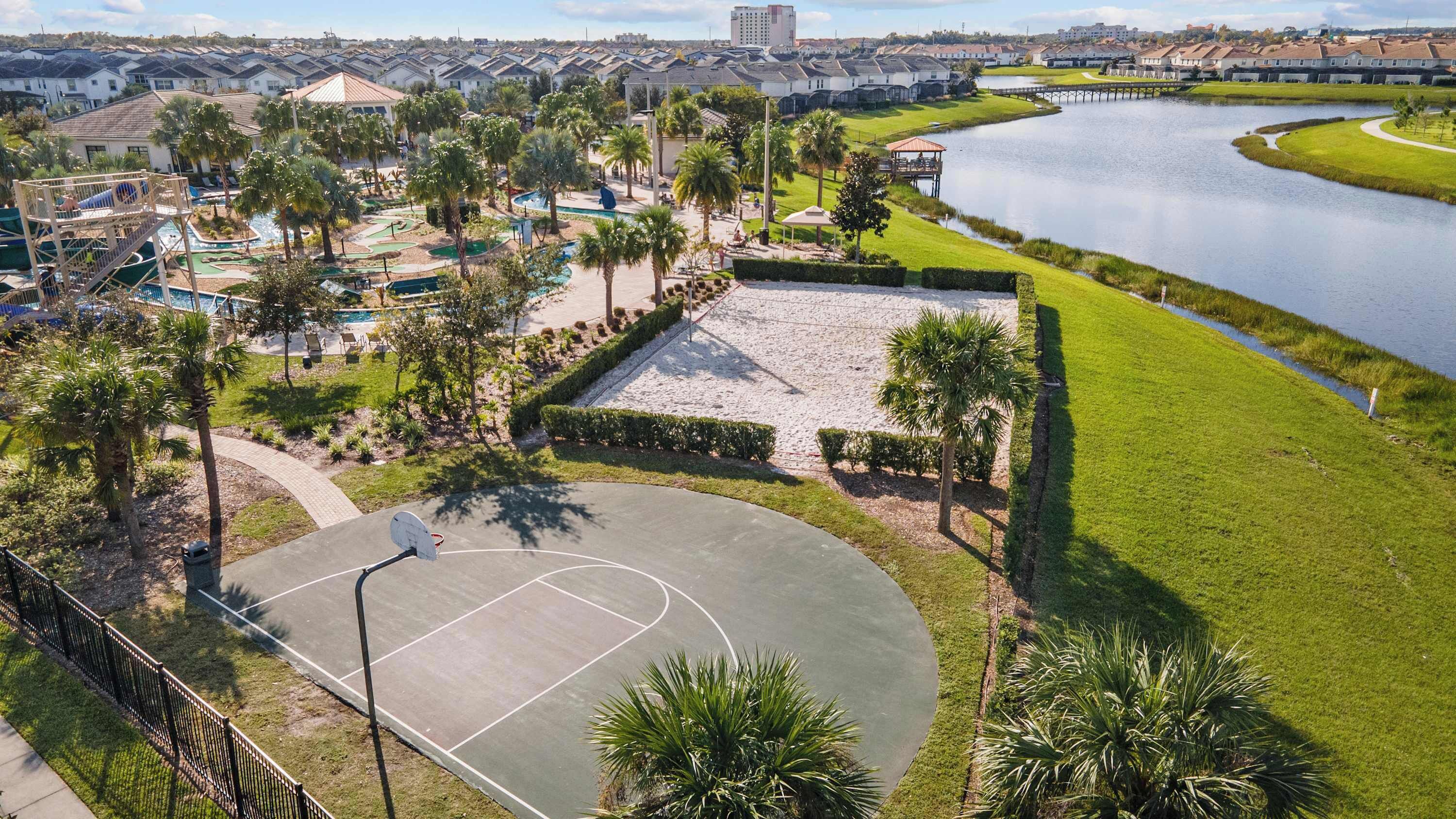 Una cancha de baloncesto rodeada de palmeras y un lago.