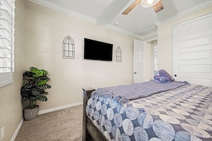 A bedroom with a bed, a television, a potted plant, and a door. - 4BR Stay | Westgate | Heated Pool, Fire Pit & BBQ (Glendale)