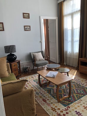 Ein Wohnzimmer mit Sofa, Sessel, Couchtisch und einem gemusterten Teppich.
