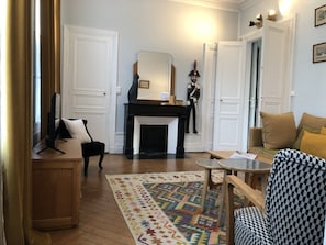 Ein Wohnzimmer mit Kamin, einer Couch, einem Couchtisch und einem gemusterten Teppich.