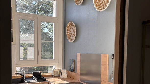 A kitchen with white cabinets, a black stove, a sink, and a window with a view of trees. - 85, l ideal, Beautiful 2-bedroom apartment in peaceful Tours near city center (Tours)