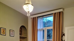 A bedroom with two beds, a chandelier, a window with curtains, and a door with a coat hook. - 85, l ideal, Beautiful 2-bedroom apartment in peaceful Tours near city center (Tours)