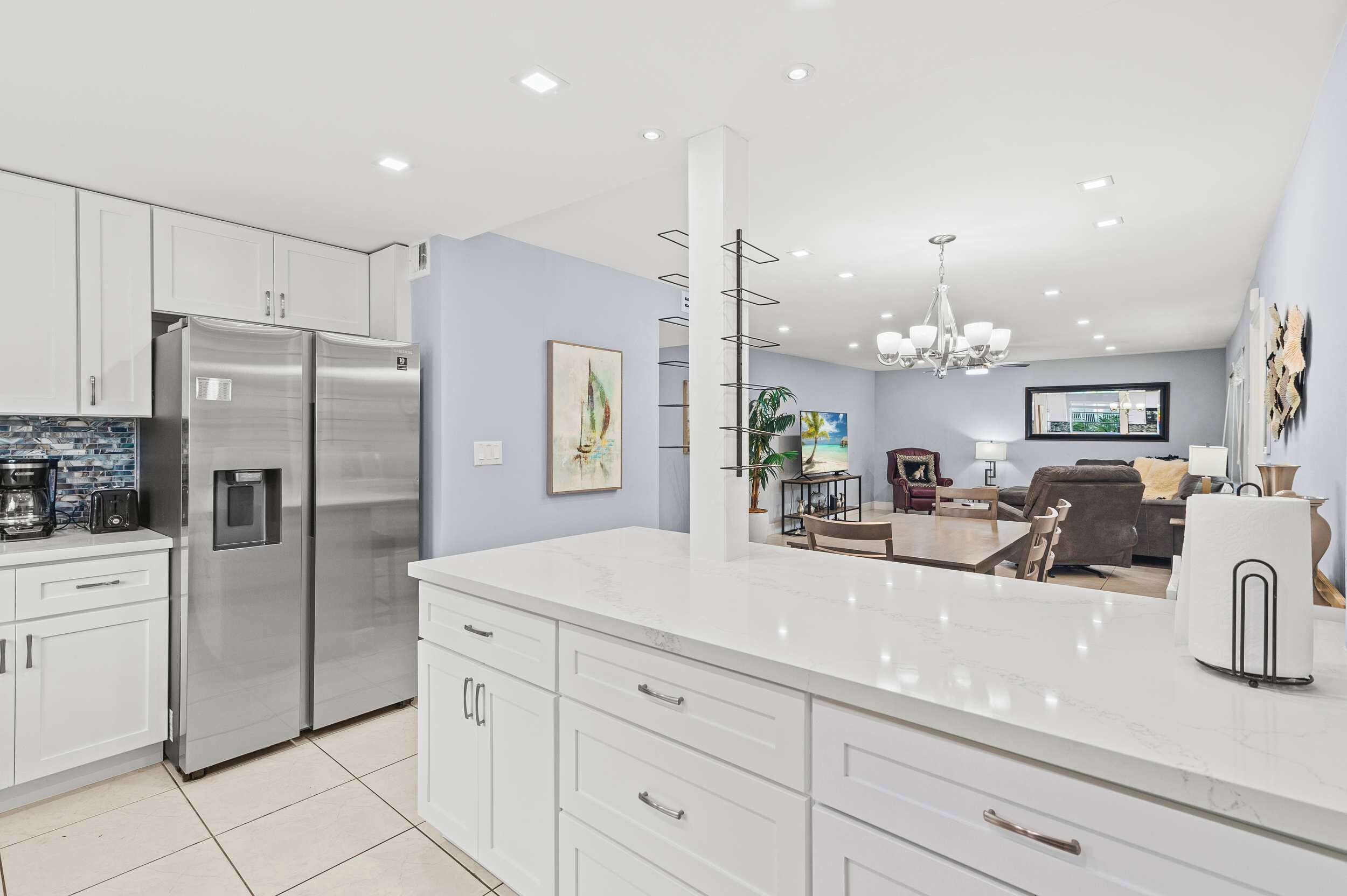 A modern kitchen with a large island, stainless steel appliances, and a dining area with a view.