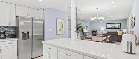 A modern kitchen with a large island, stainless steel appliances, and a dining area with a view.