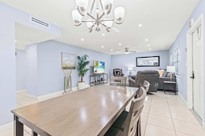 Ein geräumiges Wohnzimmer mit Essbereich, Deckenventilator und großem Fenster.