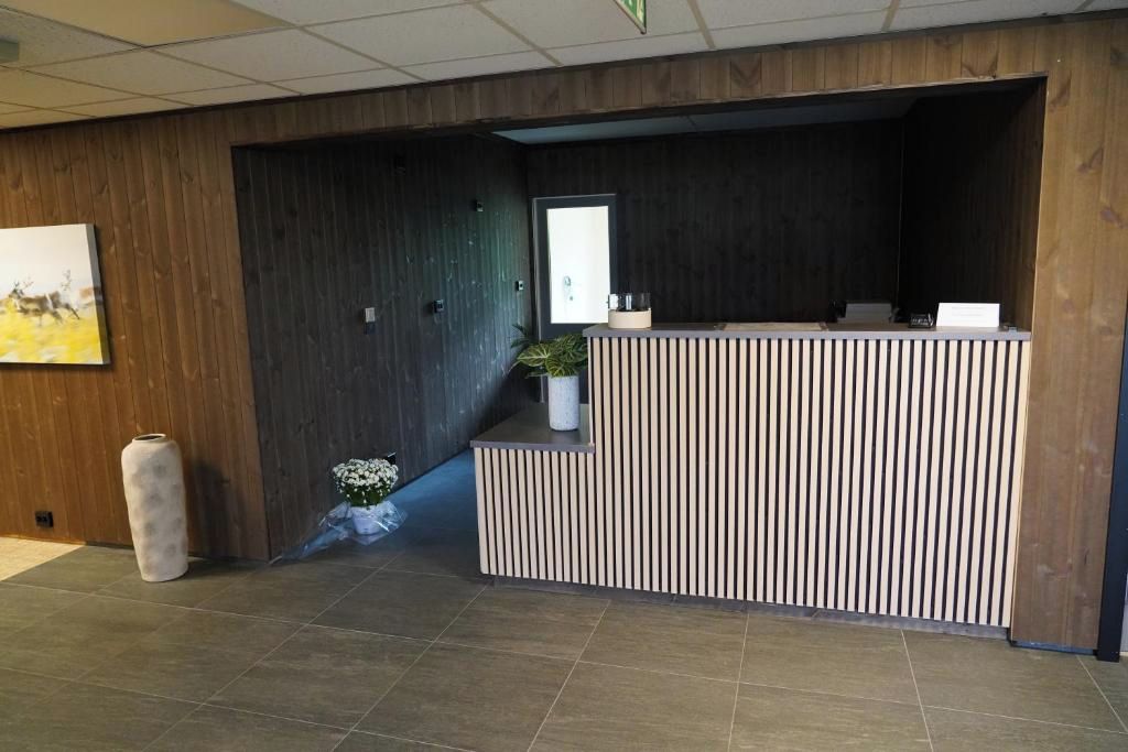 Una recepción con un diseño a rayas verticales, una planta en maceta y un cuadro en la pared.