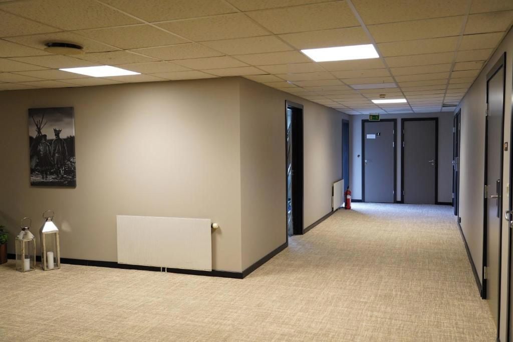 Un couloir avec un radiateur, un tableau encadré au mur et un extincteur.