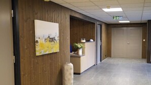 A hallway with wooden paneling, a reception desk, a large painting, and a tiled floor. - Birtavarre Aurora Adventures AS (Troms)