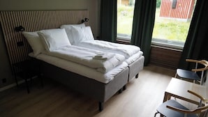 A single bed with a headboard, a bedside table, a chair, and a window with curtains. - Birtavarre Aurora Adventures AS (Troms)