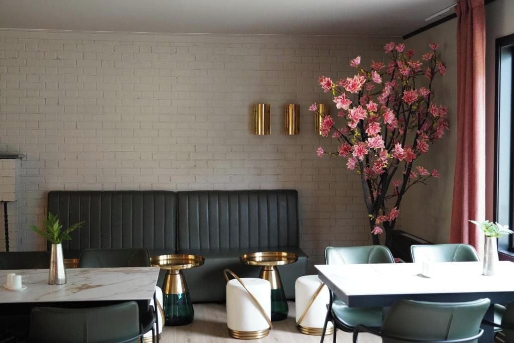 A modern dining area with a brick wall, a dark upholstered bench, and a table with green chairs.