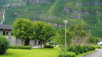 A residential area with houses, a well-maintained lawn, and a mountain backdrop.