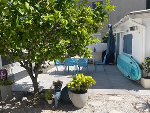 A patio area with a table and chairs, a surfboard leaning against a wall, and potted plants. - Apartment 'Cannes Three Bedrooms' with Balcony, Wi-Fi and Air Conditioning (Cannes)