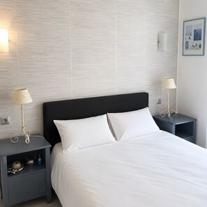 A neatly made bed with white linens, two bedside tables with lamps, and a textured wall. - Apartment 'Cannes Three Bedrooms' with Balcony, Wi-Fi and Air Conditioning (Cannes)