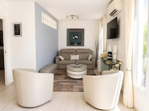 A modern living room with a sofa, two armchairs, a coffee table, and a flat-screen TV mounted on the wall. - Apartment 'Cannes Three Bedrooms' with Balcony, Wi-Fi and Air Conditioning (Cannes)