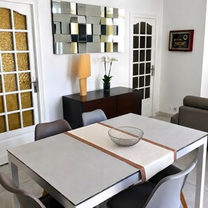 A dining area with a table, chairs, a decorative bowl, a lamp, and a mirror on the wall. - Apartment 'Cannes Three Bedrooms' with Balcony, Wi-Fi and Air Conditioning (Cannes)