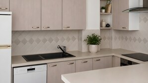 Uma cozinha moderna com armários de madeira clara, uma pia preta e uma máquina de lavar louça.