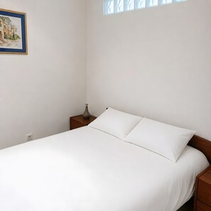 A simple bedroom with a bed, a nightstand, a vase, and a framed picture on the wall. - Apartment 'Cannes Three Bedrooms' with Balcony, Wi-Fi and Air Conditioning (Cannes)