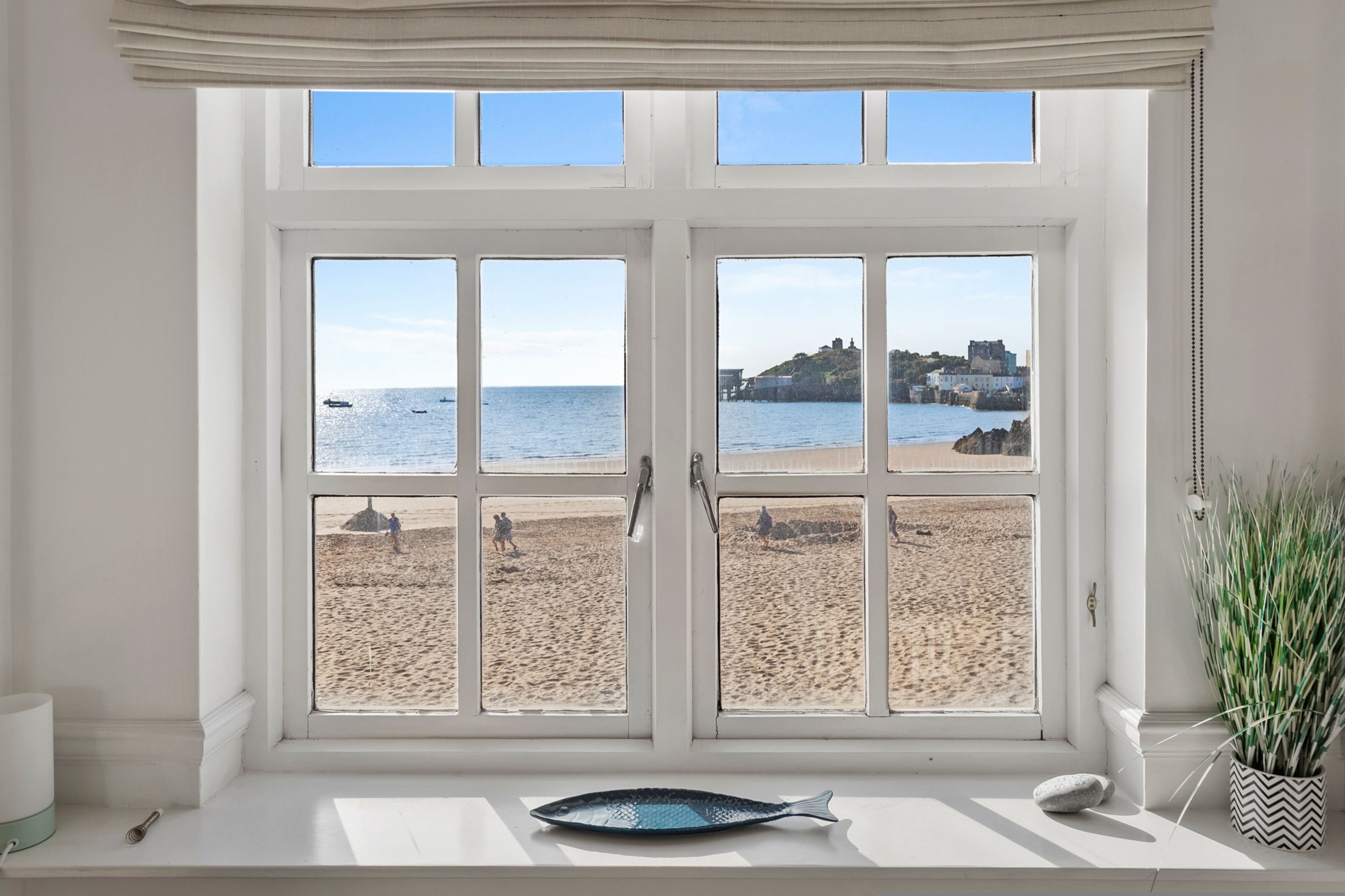 A window with a view of a beach and the sea.