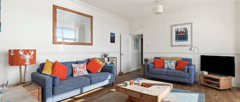 Una sala de estar moderna con dos sofás, una mesa de centro y un televisor de pantalla plana.