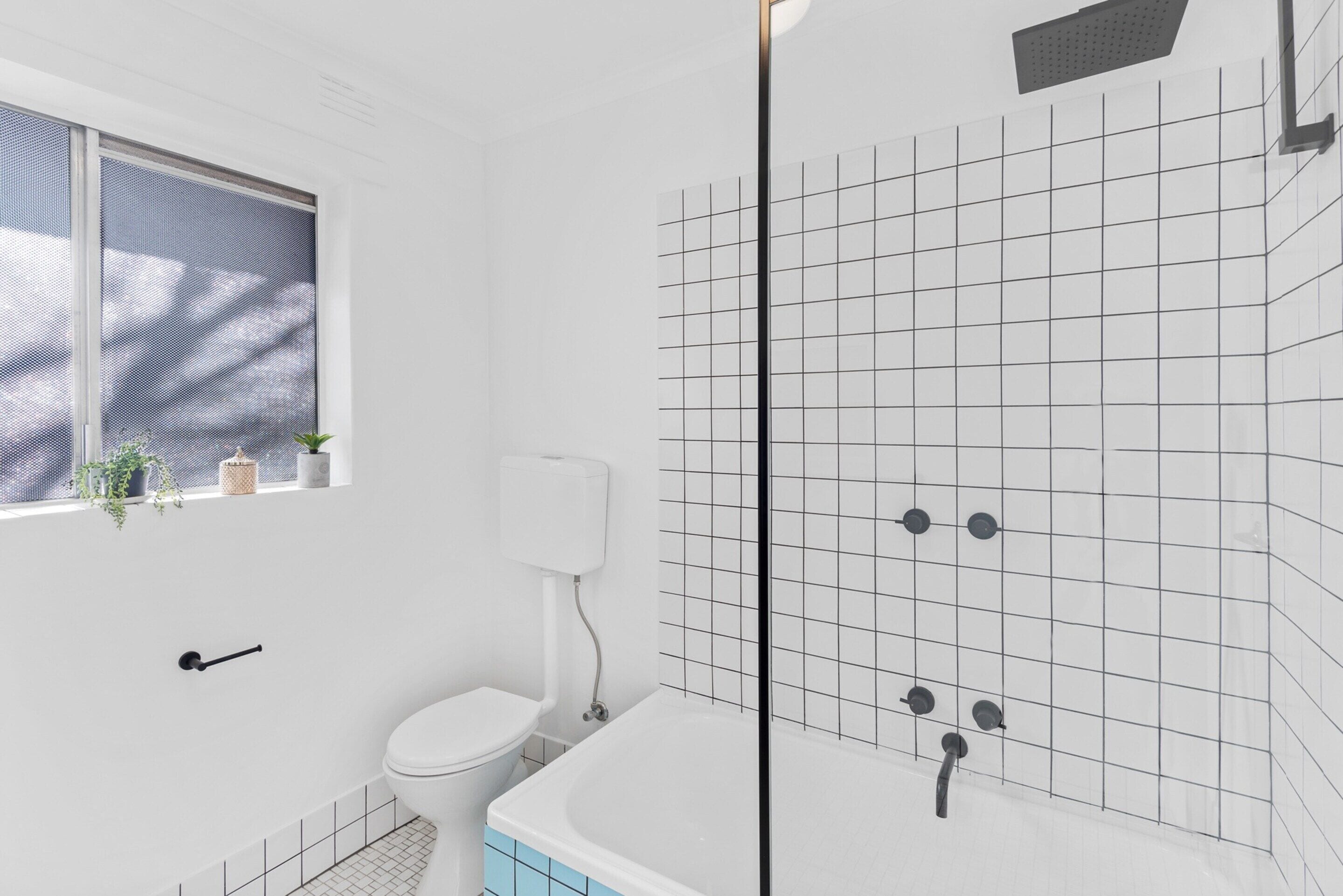 A modern bathroom with a toilet, bathtub, and shower.