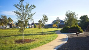 A residential area with a curved pathway, young trees, and houses in the background. - Bright 1-bed Retreat in Kingsville (Melbourne)