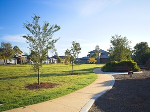 A residential area with a curved pathway, young trees, and houses in the background. - Bright 1-bed Retreat in Kingsville (Melbourne)