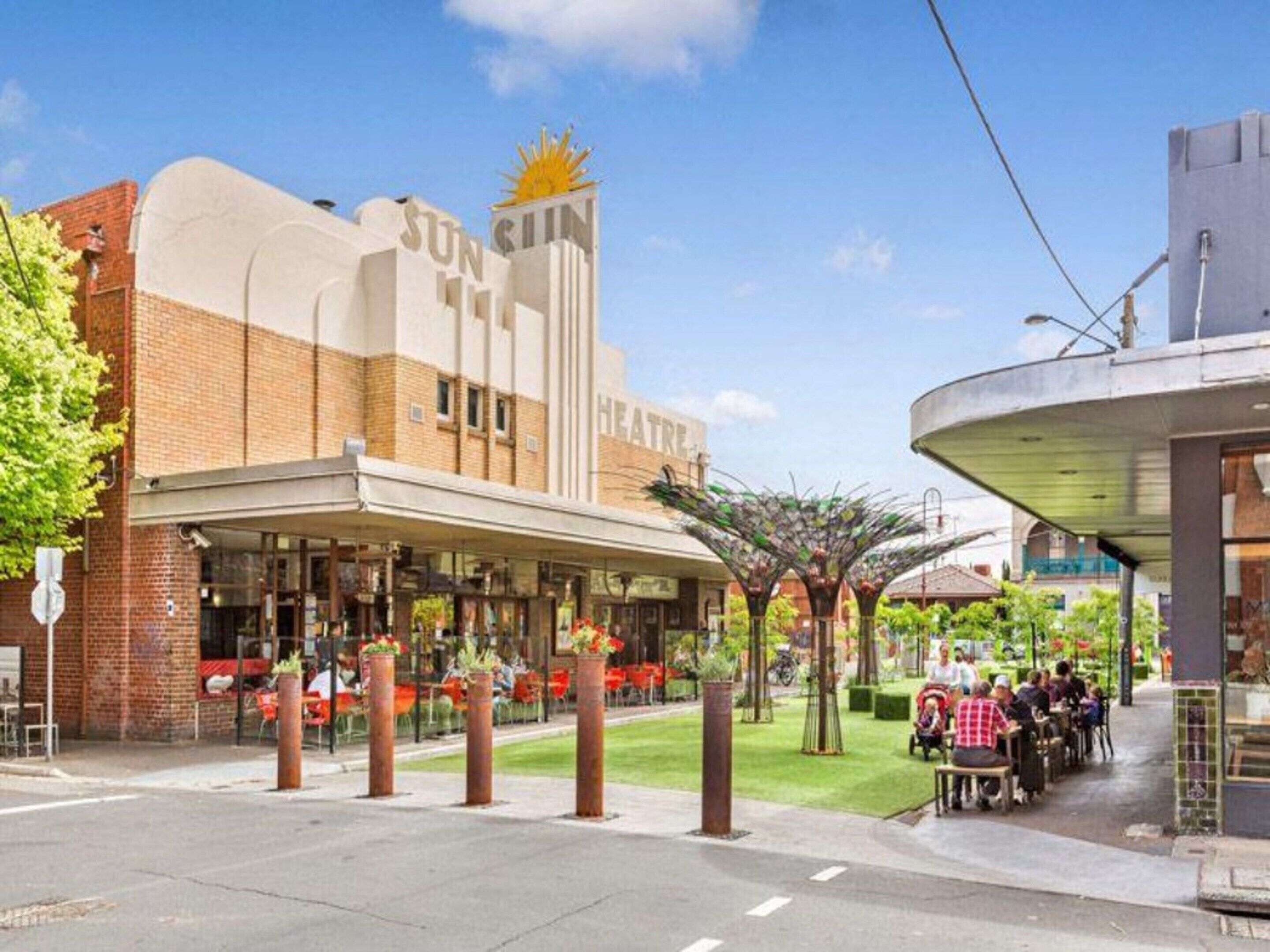 A theater with a marquee reading 'SUN CITY THEATRE' and a covered outdoor seating area.