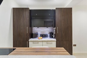 A modern kitchen with wooden cabinets, a countertop, and a built-in oven. - Monkstone View - Direct Beach Access (Saundersfoot)