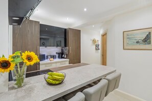 Eine moderne Küche mit Marmorarbeitsplatte, Holzschränken und einem Essbereich mit einer Bank.