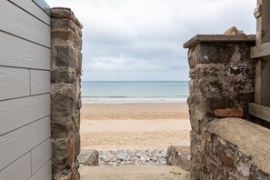 A beach view through a stone archway leading to a wooden building. - Monkstone View - Direct Beach Access (Saundersfoot)