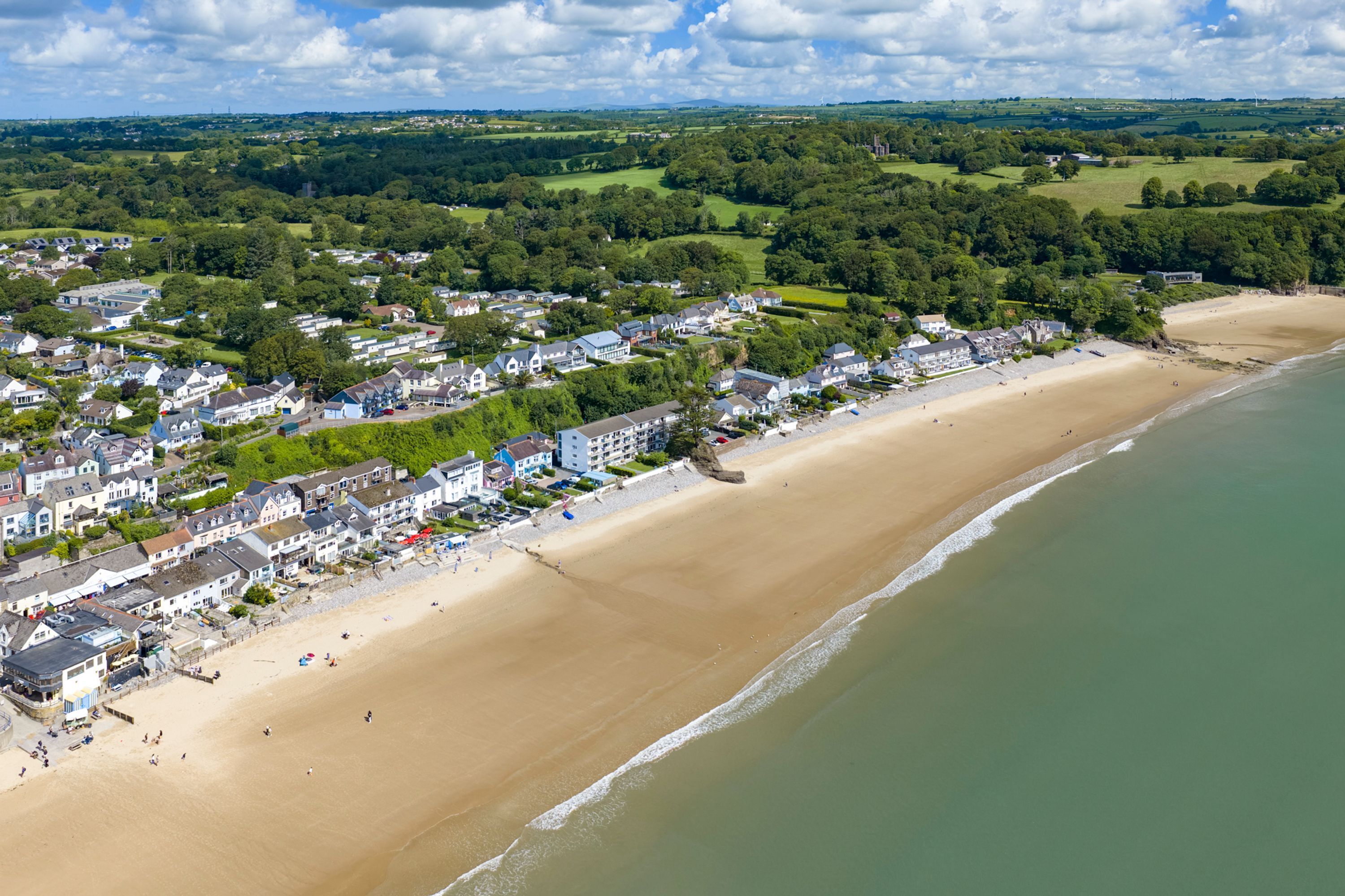 A coastal town with a sandy beach and a row of houses along the shore.