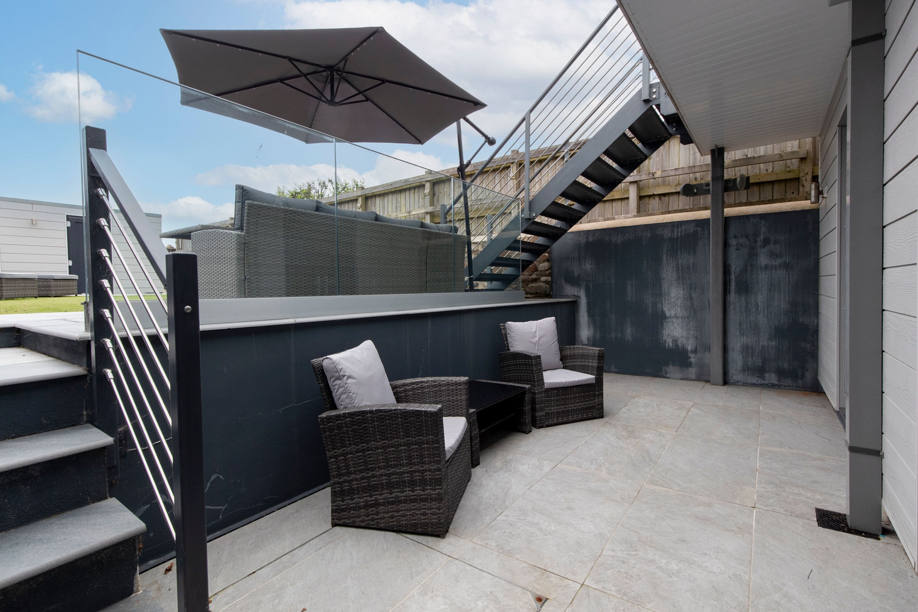A patio area with outdoor furniture, a staircase, and a large umbrella.