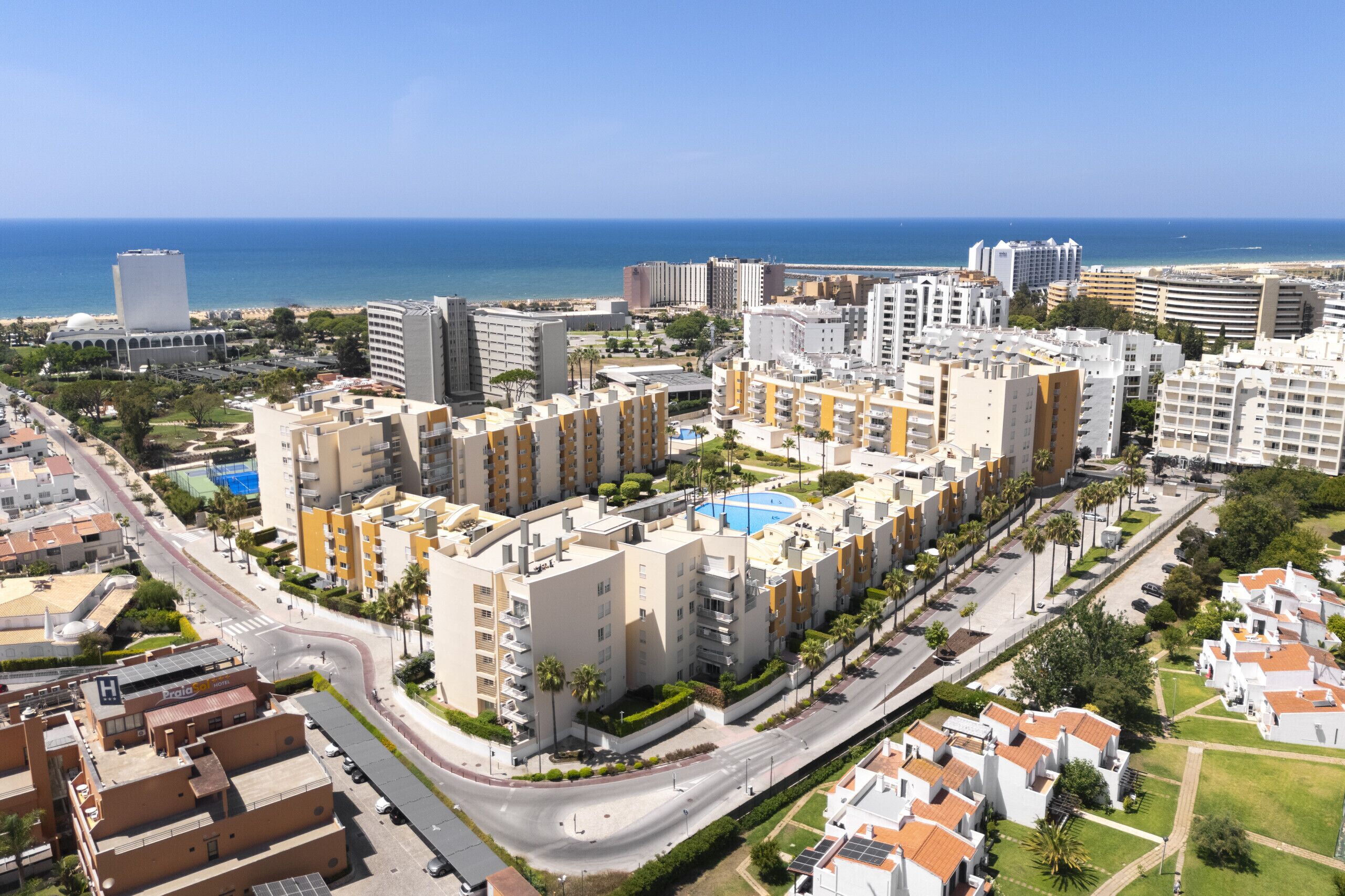 Un paysage urbain côtier avec des immeubles modernes de grande hauteur, une marina et une vue dégagée sur la mer.