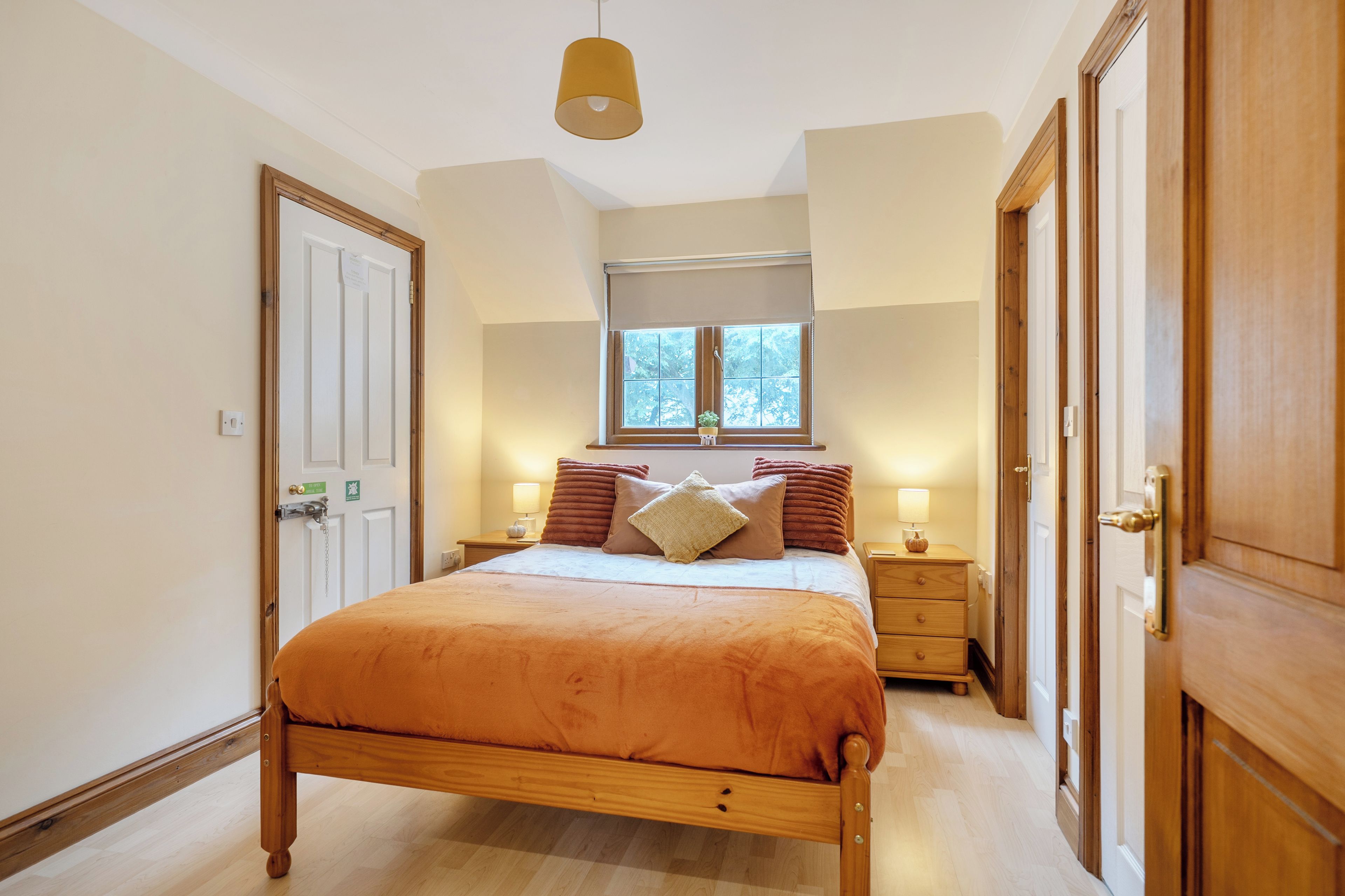 A bedroom with a bed, bedside tables, a window, and a door.