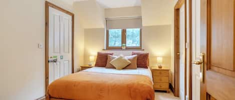 A bedroom with a bed, bedside tables, a window, and a door.