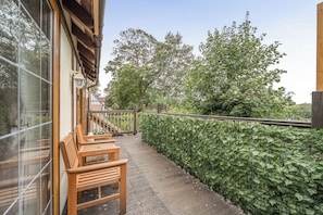 A wooden bench outside a building with a glass wall, a wooden staircase, and a hedge. - 2-bed - Sleeps 4 - Parking & Ev Charging (Wadebridge)