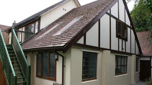 A traditional half-timbered house with a visible staircase and a chair outside. - 2-bed - Sleeps 4 - Free Parking & Ev Charging (Wadebridge)