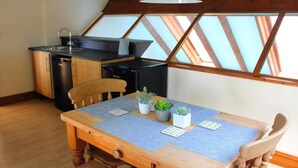 A compact kitchen with a dining table, chairs, and a ceiling fan. - 2-bed - Sleeps 4 - Free Parking & Ev Charging (Wadebridge)